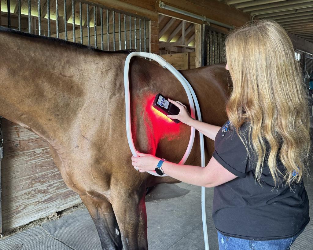 A woman applying dual modalities of ROC Red Light therapy and PEMF therapy via the MagnaWavePEMF XL Wave Wings attachment