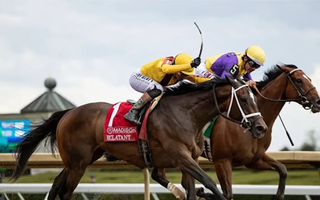 Jockeys in yellow and purple silks racing two horses neck-and-neck down the track, with the lead horse's saddle towel reading "Eclatant"